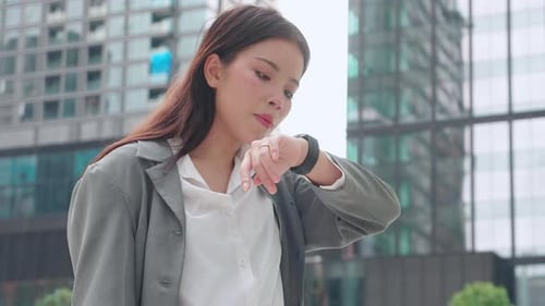 Young Woman Checks Smartwatch in City Environment