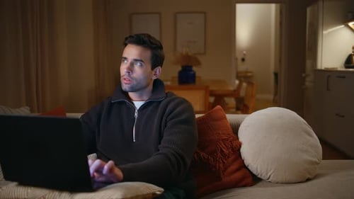 Man Using Laptop on Couch at Night