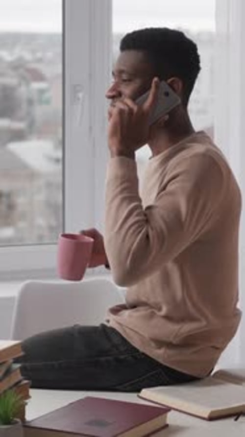 Young Adult Using Smartphone Near Bright Window