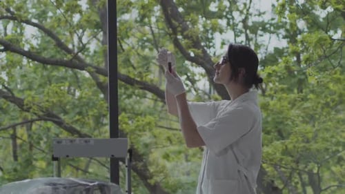 Female scientist checking blood sample in green laboratory with big windows