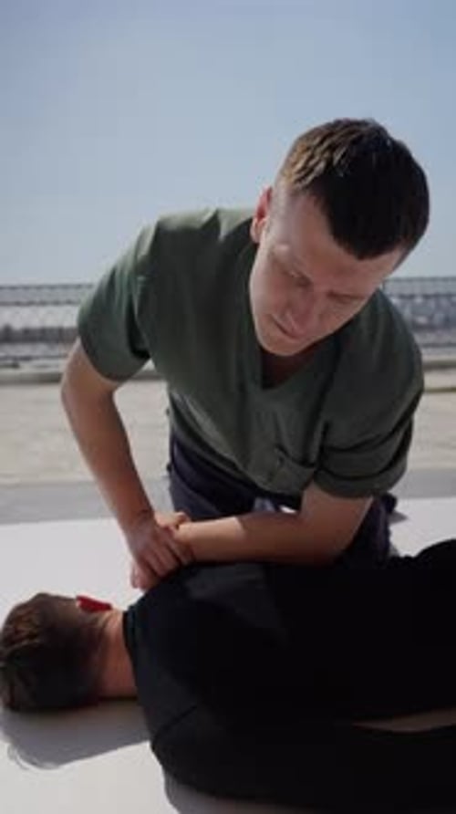 Man presses on another man's back outdoors