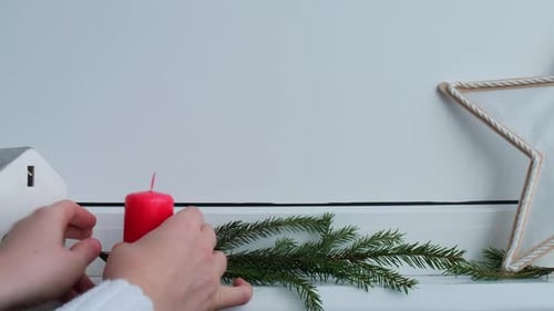 Frau bereitet sich auf Silvester und Weihnachten vor: Vier rote Adventskerzen auf weißer Fensterbank, handgemacht