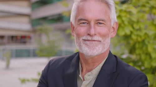 Confident Senior Businessman Smiling Outdoors Near Modern Building