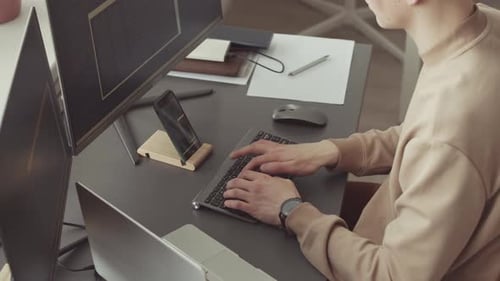 Young Adult Coding at Desk with Dual Monitors