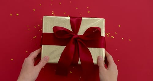 Festive Gold Gift Box with Red Ribbon on Red