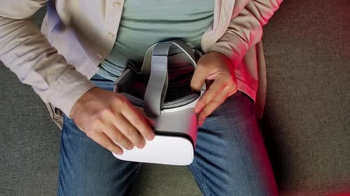 Man Sitting on Sofa Holding Virtual Reality Headset