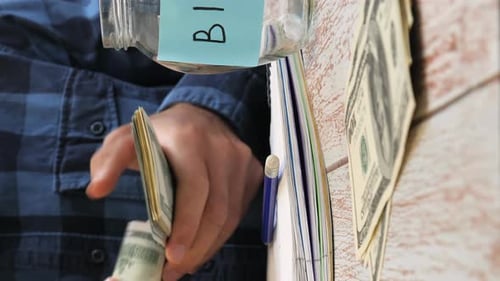 Saving money to buy bike. Man counting and putting money in jars. Vertical video