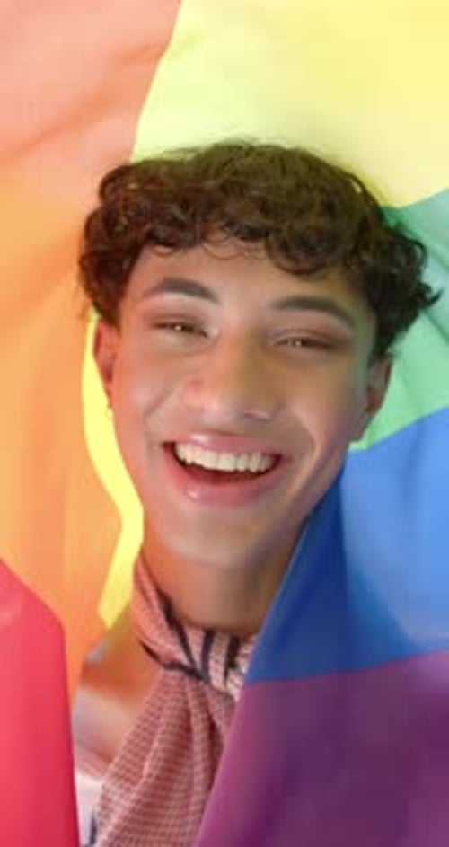 Smiling Young Adult Wrapped in Rainbow Flag