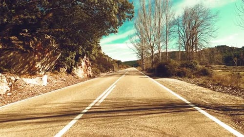 Driving vehicle on a long asphalt straight road in the nature with blue sky