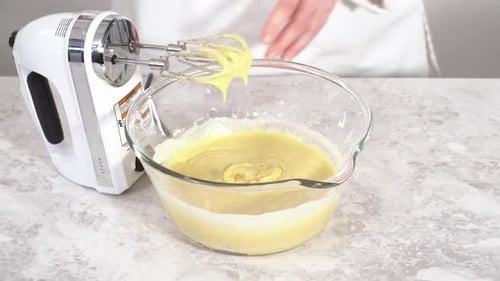 Nahaufnahme, wie Zutaten in einer Glasrührschüssel gemischt werden, um den Funfettti Bundt-Kuchen zu backen