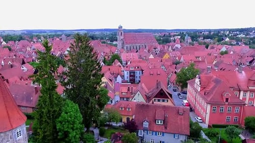 a drone flies backwards over the old town and the red roofs of the houses and the city's green park