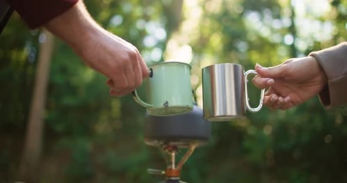 Hands, couple and cheers with coffee in forest for travel date, hiking break and bonding together