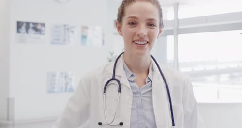 Portrait of happy female doctor with stethoscope smiling in hospital, in slow motion