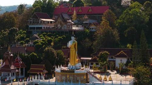 Golden Buddha Statue Standing Tall Within Peaceful Buddhist Temple Verdant Landscape Framing Ornate