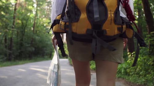 Backpacker Walks Through the Sunny Forest with Map