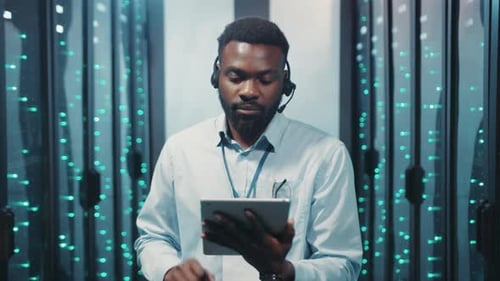 Man in Data Center Using Tablet and Smiling