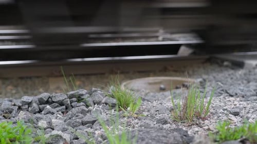 Die Räder eines Zuges auf der Bahnstrecke fahren an der Kamera vorbei. Nahaufnahme.