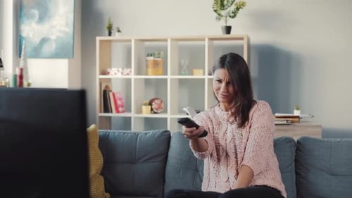 Woman Changing Channels on Television in Living Room