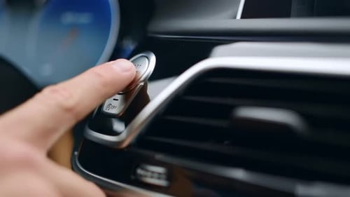 Male hand igniting a luxurious car engine with a modern start stop button in slow motion