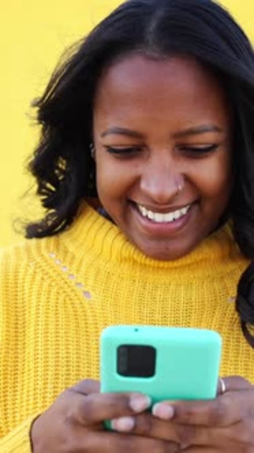 Woman Uses Mobile Phone Against Yellow Wall