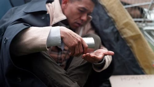 Man Counting Coins in Urban Setting