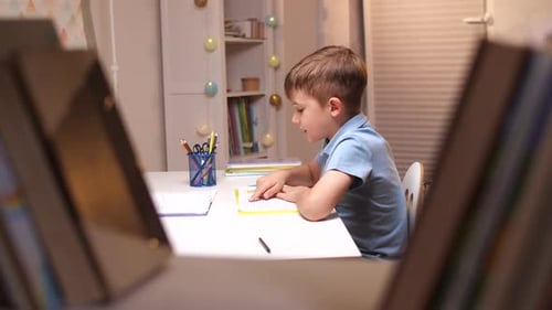 Boy Reading Book at Table Indoors