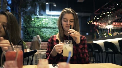 Teenage girlfriends enjoying fresh drinks and casual conversation in a bright cafe