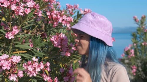 Woman with Blue Hair Sneezing by Pink Flowers