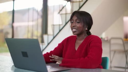 Afrikanerin sitzt drinnen zu Hause und führt einen Videoanruf, während sie ihren Laptop benutzt