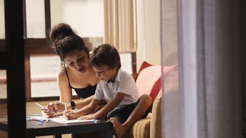 Woman and Child Drawing at Table Indoors