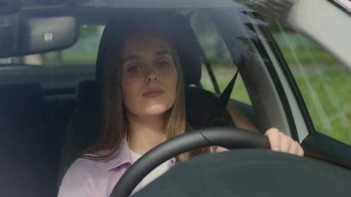 Young Woman Driving Car and Looking Around at Road Traffic of Green