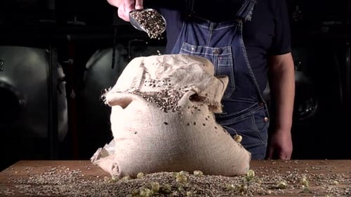 Seeds Pouring into Burlap Bag on Wooden Table