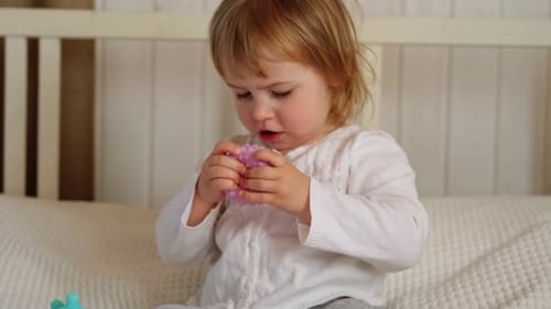 Little Girl Plays with Textured Ball at Home