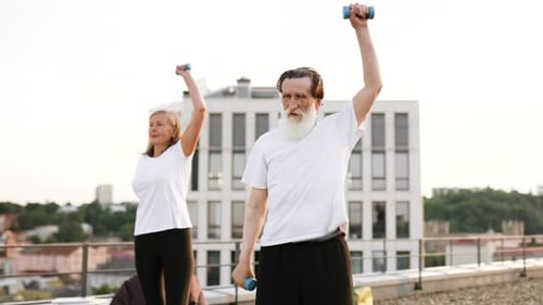 Mature Couple Lifting Weights on City Rooftop
