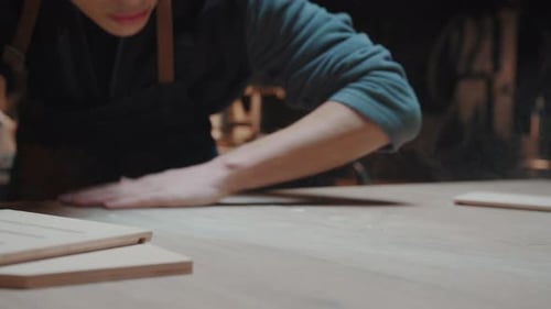 Young Man Cleaning Woodworking Bench in Workshop