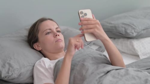 Woman Uses Smartphone Lying in Bed