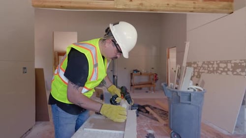 Construction Worker Drilling Wood Inside Building