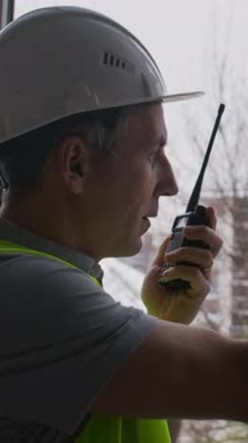 Construction Worker Communicates on Walkie Talkie in Urban Setting