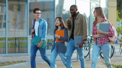 Four Happy Multiethnic Friends Walking Out of Campus University Talk Loudly Chatting Have Fun