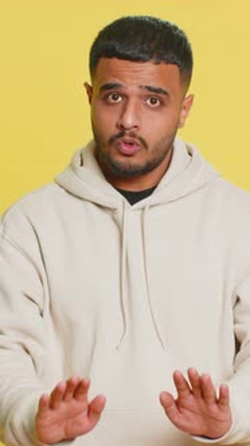 Young Man Gesturing with Hands and Talking on Yellow