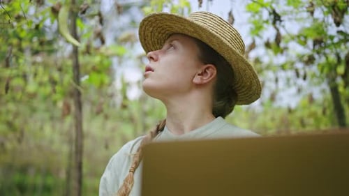 Female Farmer with Laptop Inspecting Gourd Harvest on Vegetable Farm Young Woman Agronomist Checking