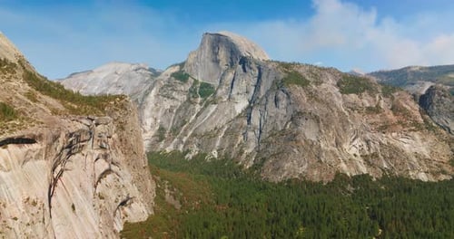 Grey rocks towering over pine tree woods. Yosemite National Park in California on sunny daytime.