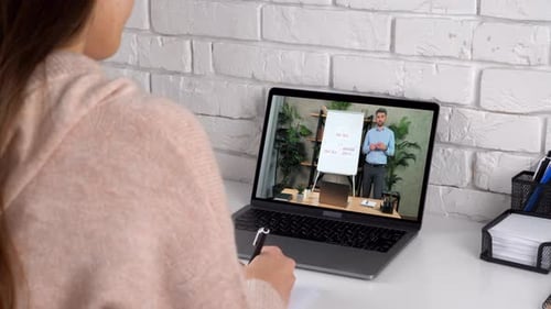 Frau lernt zu Hause, Online-Videoanruf, Laptop schreibt ins Notizbuch, Lehrer zuhören