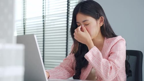 Exhausted Asian young businesswoman overwork late in office workplace.