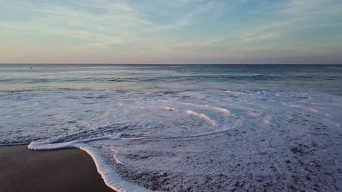 Aerial drone wide angle of flying over calm ocean waves at beach at day