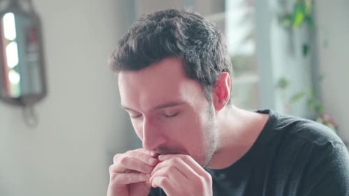Slow motion young caucasian man bites into burger at home, cheeseburger eating enjoyment, close up p