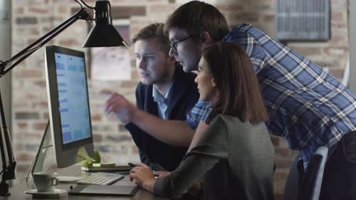 Equipe de jovens designers está discutindo um projeto de trabalho em uma tela de computador.