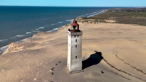 Lighthouse Towering Over Sand Dunes Near Ocean Shoreline