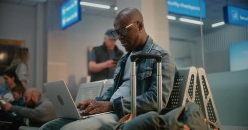 Man Using Laptop Doing Remote Work Waiting for Flight in Boarding Lounge of Airline Hub