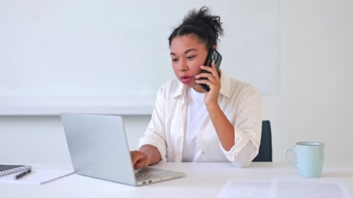 Woman Works and Talks on the Phone in Office